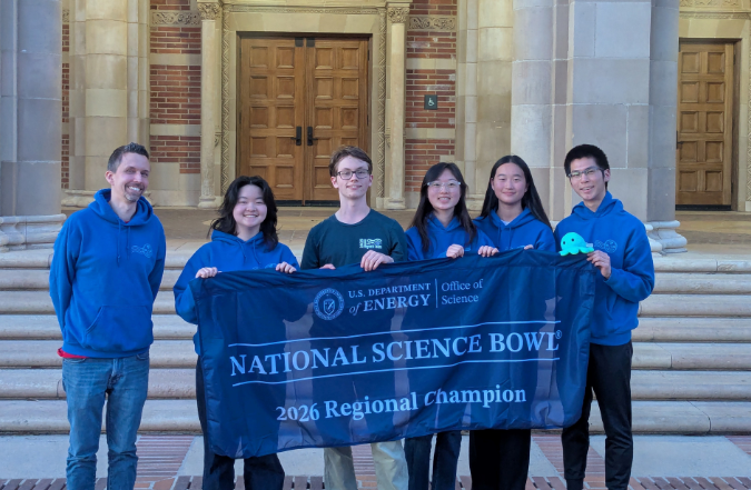 Uni's science bowl team posing with championship banner in front of UCLA building