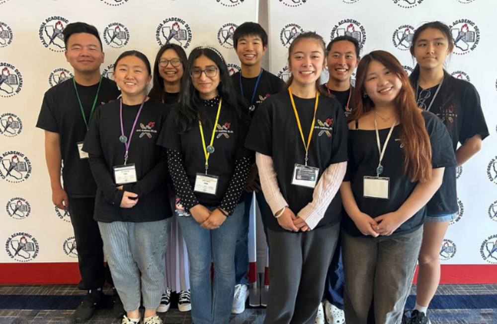 A group of smiling students in black t-shirts stand together, posing for a photo.