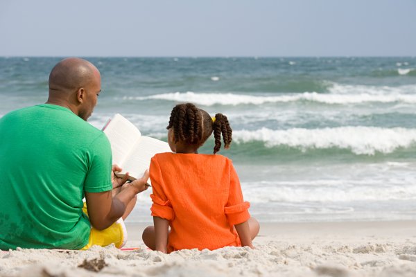 Father and daughter reading on the beach
