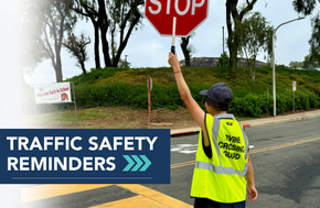 A crossing guard holds a stop sign, directing traffic near a school.