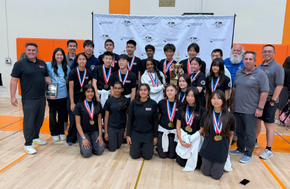 Sierra Vista team and coaches pose for a photo, holding a trophy and a plaque, all wearing medals.