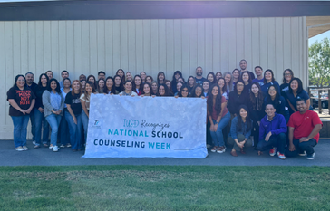 School Counselors smiling in group photo; holding "National School Counselor Week" sign
