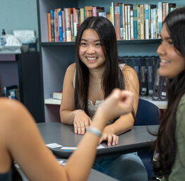three smiling female students sitting at a table