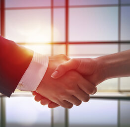 two hands shaking in front of a window of a conference room