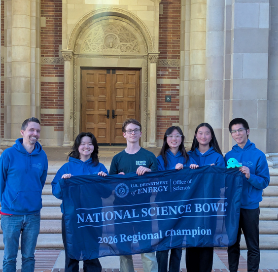 Uni's science bowl team posing with championship banner in front of UCLA building