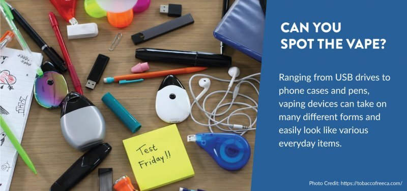 Desk cluttered with various items, some are vapes that look like typical student stationary.  The text reads: Can you spot the Vape?  Ranging from USB drives to phone cases and pens, vaping devices can take on many different forms and easily look like various everyday items.