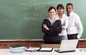 two female teachers and a male teacher posing in front of a blackboard in classroom