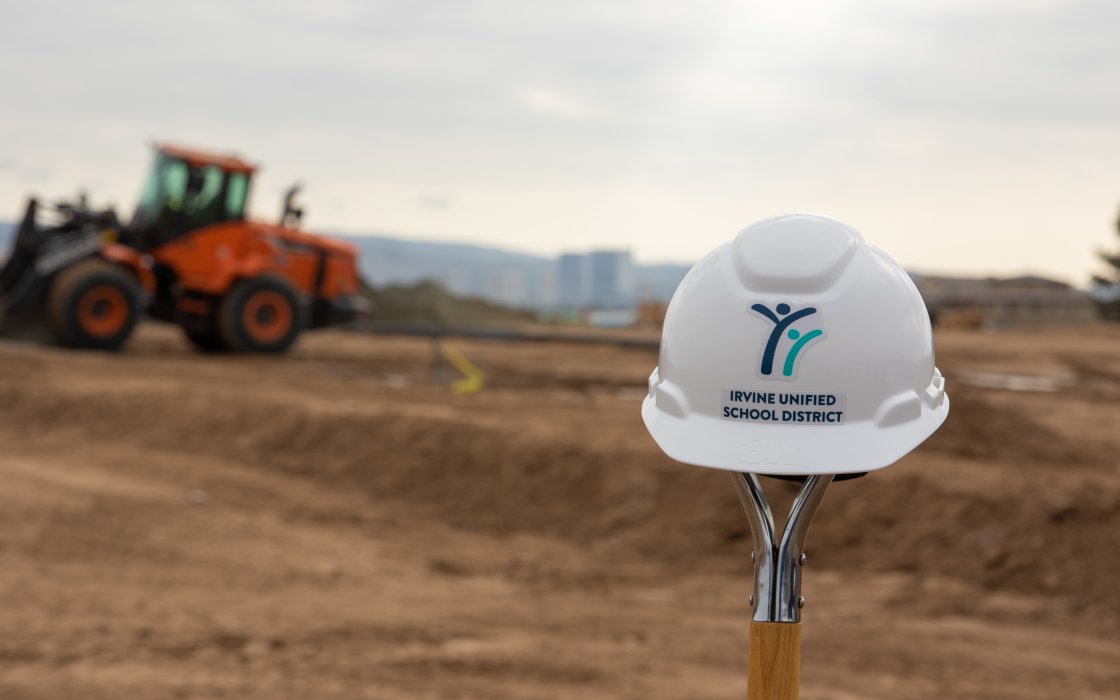 IUSD hard hat in front of construction site