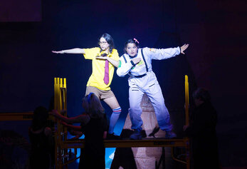 Two students perform a choreographed duet in Portola High School’s “SpongeBob,” standing on a raised platform under a spotlight.