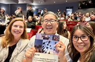 Board of Education members Dr. Jeff Kim and Katie McEwen smiling and holding event program with IUSD AVID coordinator Jenny Thai