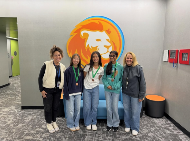 Solis Park School Science Olympiad medalists wearing medals posing with school staff in front of school logo.