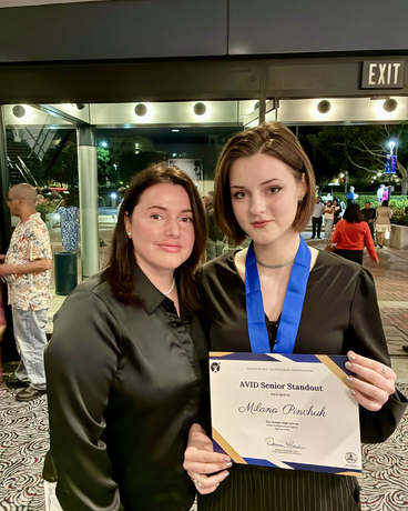 Milana Pinchuk holding award and standing with family member