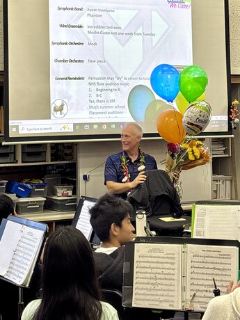 Henry Miller smiling with balloons behind him in classroom
