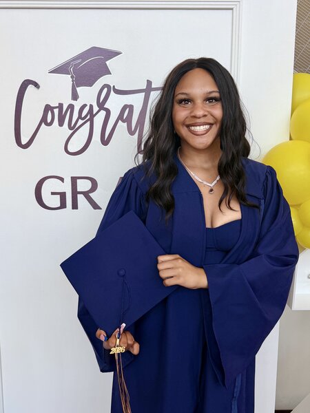 Camille Debrick in front of graduation sign