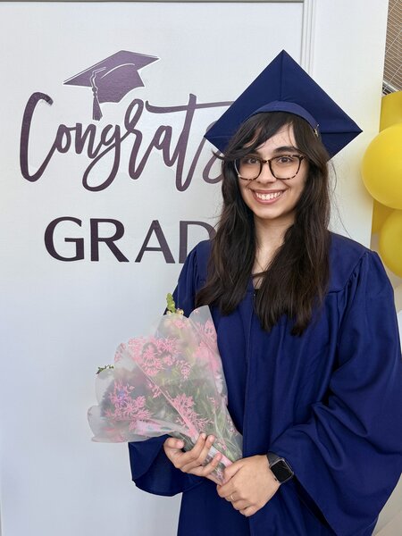Jasmine standing in front of graduation sign
