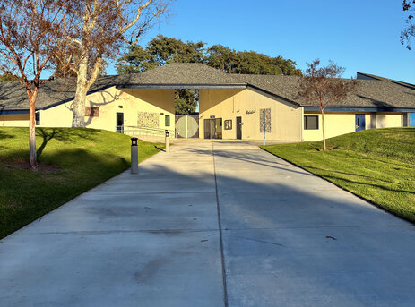 xterior view of a cream-colored school building (culverdale) with a wide concrete walkway and grassy hills