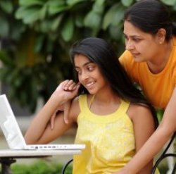 daughter and mother in yellow shirts looking at laptop