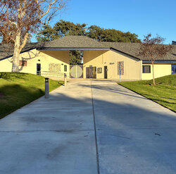 xterior view of a cream-colored school building (culverdale) with a wide concrete walkway and grassy hills
